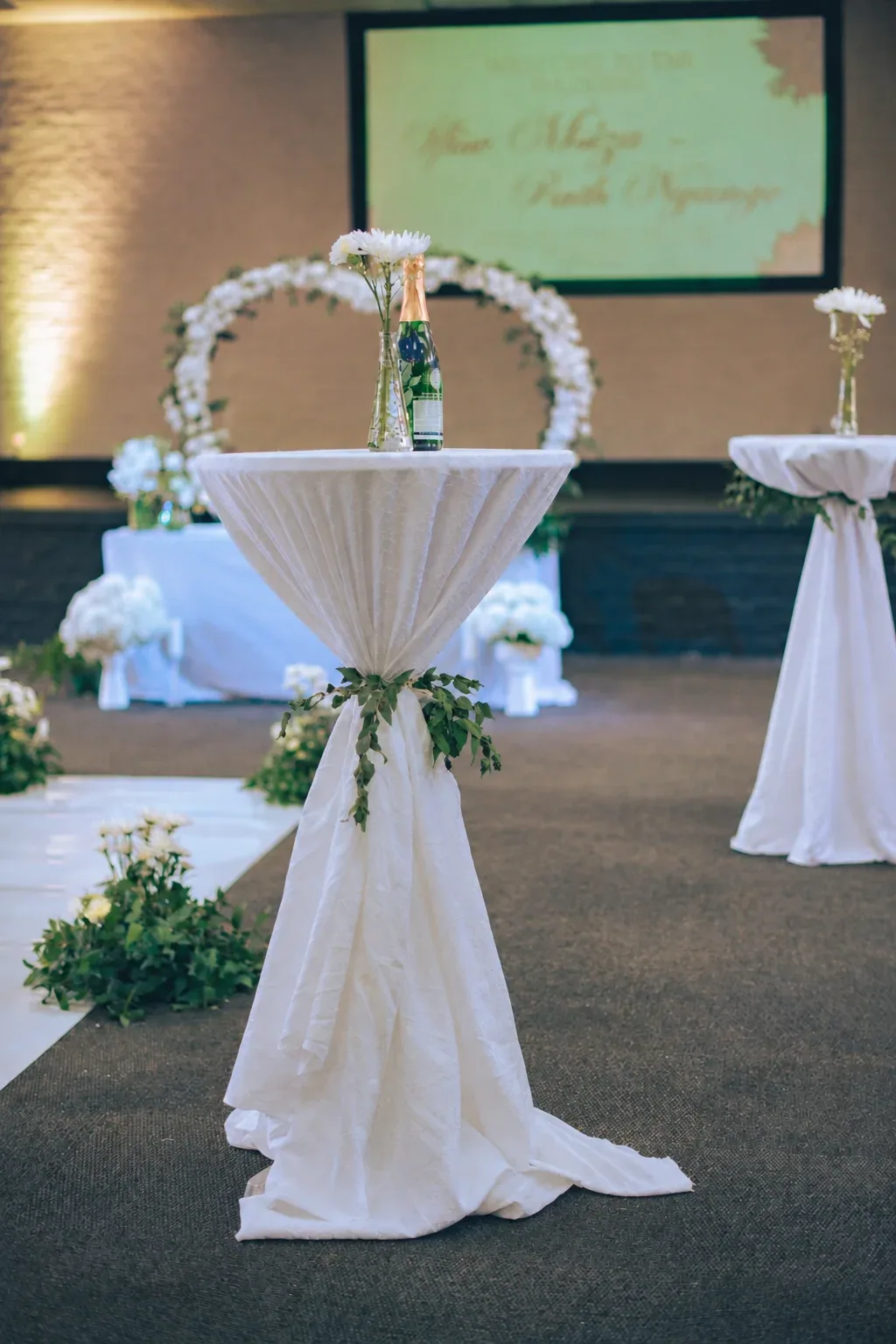 Ceremony backdrop with white draping and a floral arch